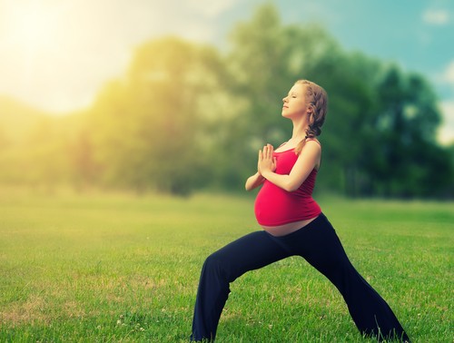 pregnant woman doing yoga in the park 
