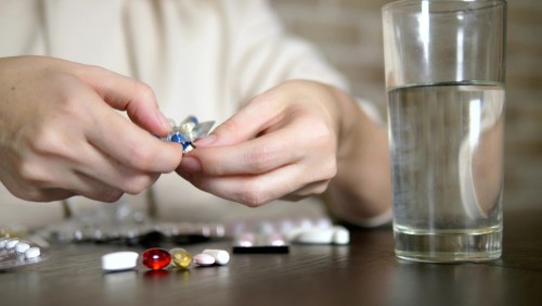 woman with many medicines on her table with a glass of water