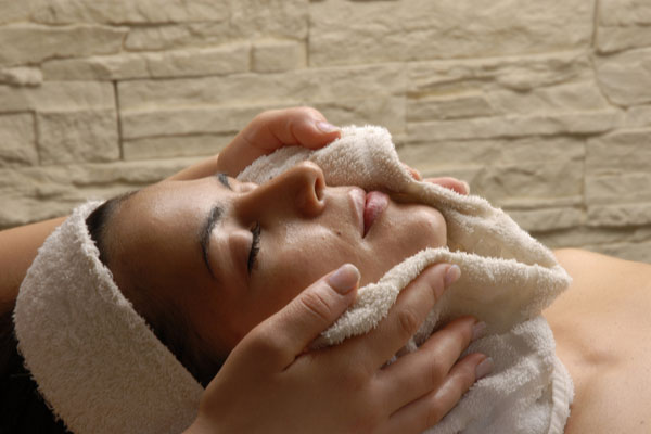 Girl with eyes closed with warm towel on face