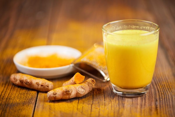 Glass of turmeric milk with turmeric pieces