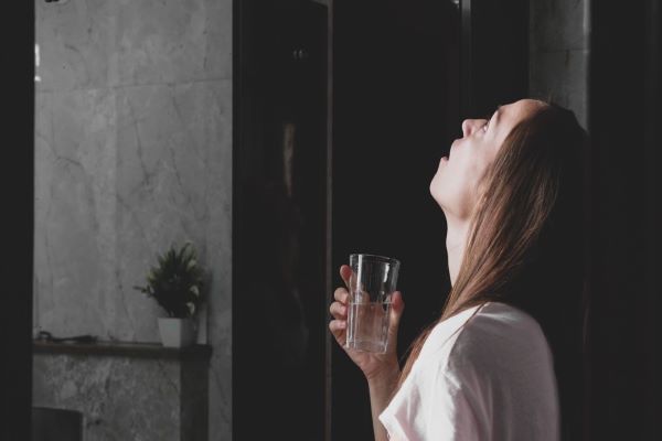 a girl girgling with a glass of water in hand