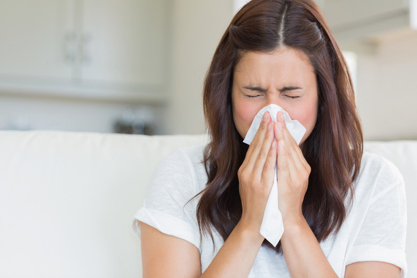 girl sneezing with a tissue in hand