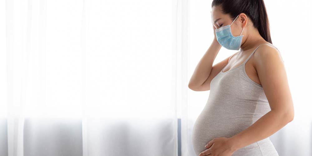 sick pregnant female wearing a mask