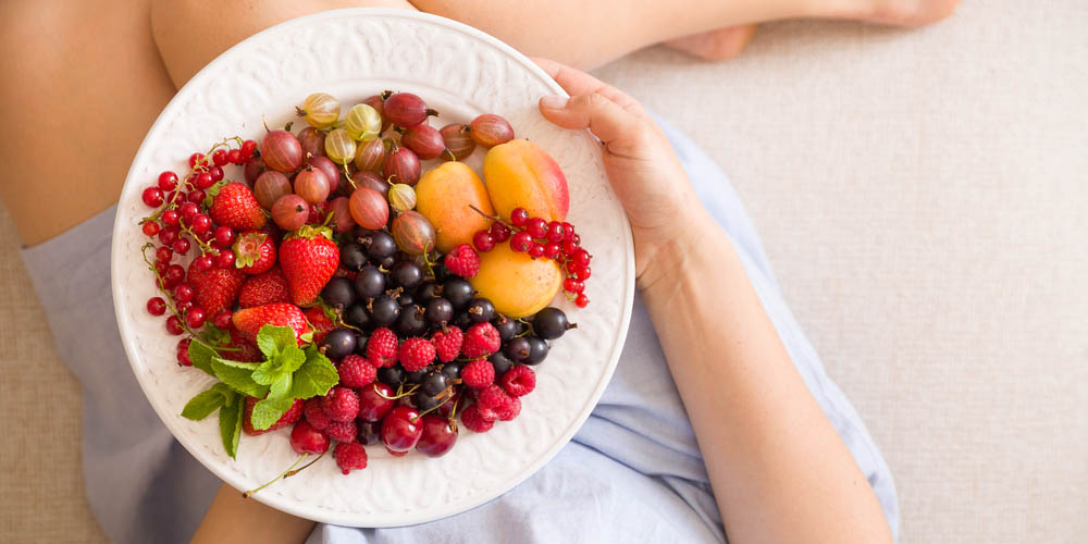 female having plate full of fruits