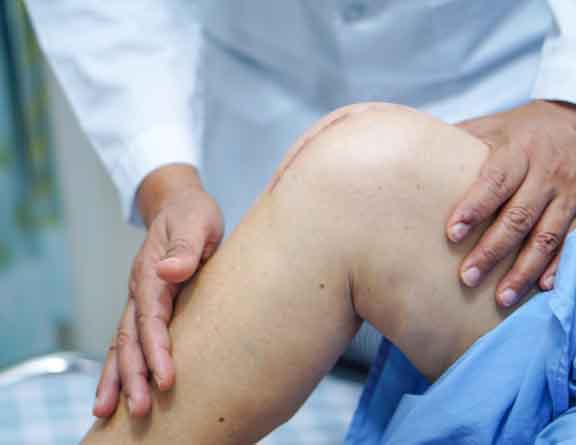 Doctor examining patient's knee after knee replacement surgery