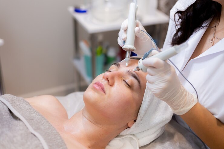 An image of a close-up of the Hydrafacial tool applying serum to the eye area of a relaxed client.